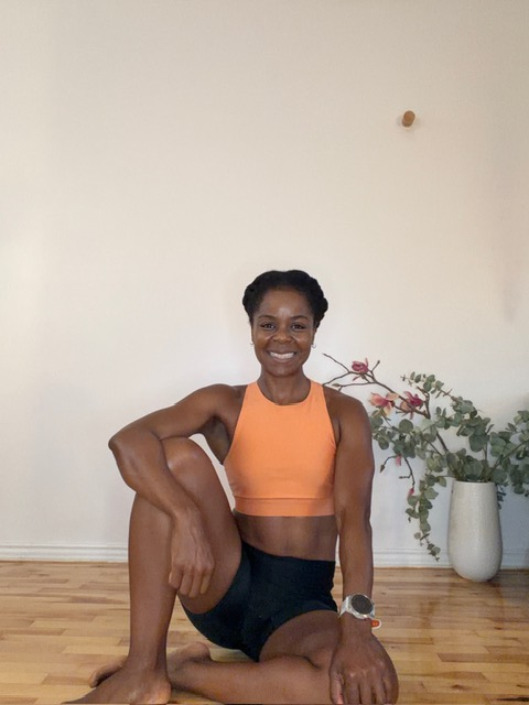 Dani smiling in workout gear on a wooden studio floor